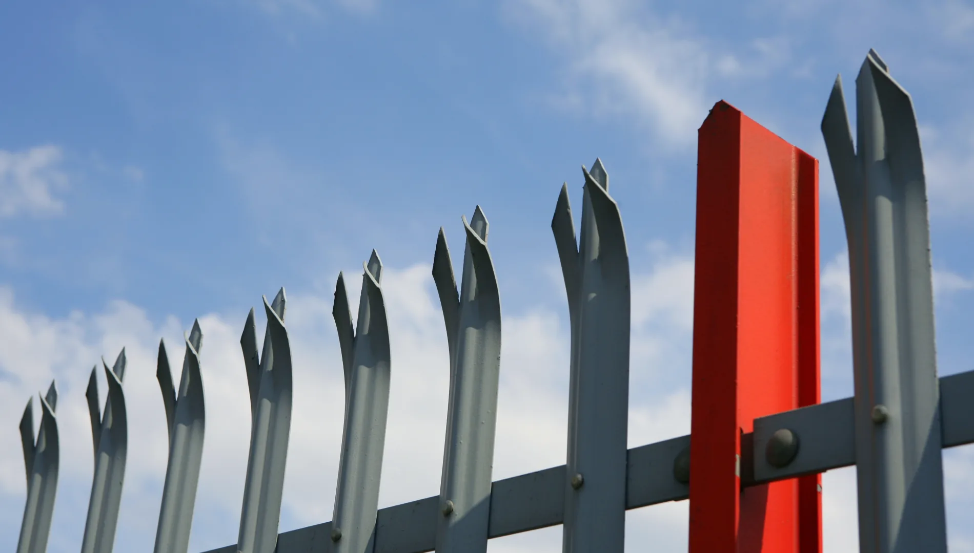 Galvanised steel palisade security fencing against a clear sky — Evenii commercial fencing