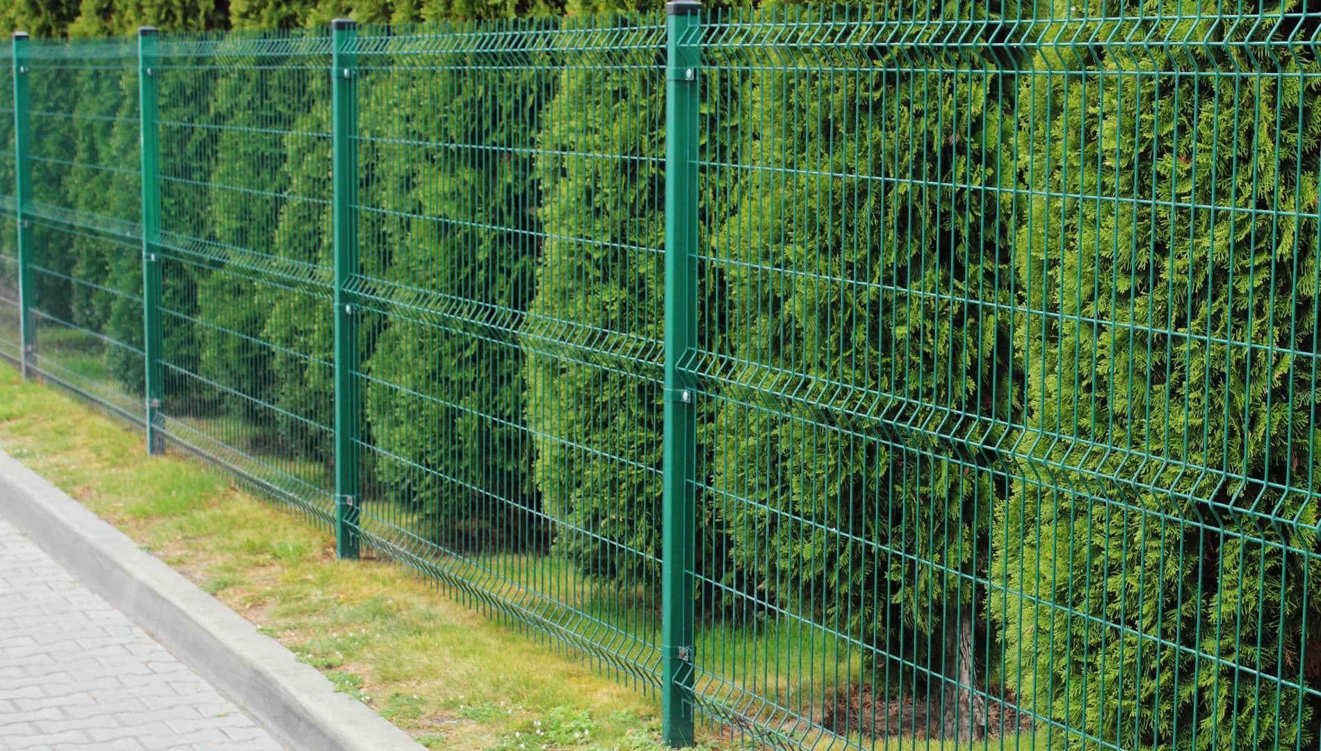 Green welded-mesh perimeter security fencing on an industrial site — Evenii commercial fencing