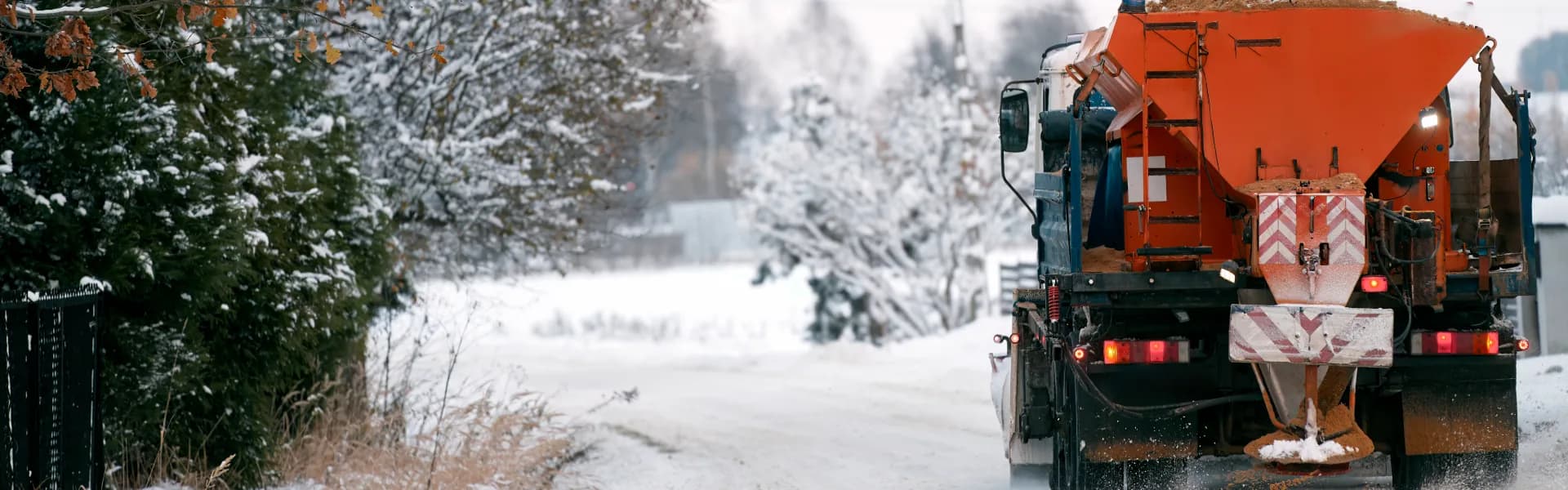 Gritter spreading rock salt along a snow-covered carriageway — winter gritting services Northeast England